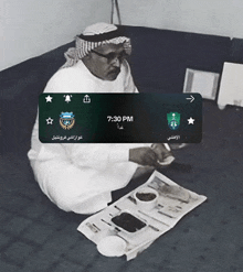 a black and white photo of a man sitting on the floor with a time of 7:30 pm on the screen