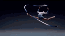 a female gymnast is jumping through the air while holding a ribbon