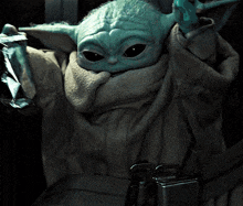 a baby yoda is sitting in a car and holding a can of soda