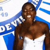 a woman in a white strapless dress is standing in front of a sign that says devil .
