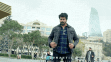 a man in a plaid shirt is standing in front of a building with mr romantic written on the bottom
