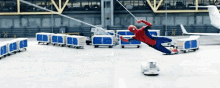 a man in a spiderman costume is flying through the air in front of a plane .