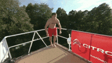 a man is jumping off a diving board next to a sign that says citro