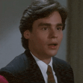 a man in a suit and tie is smiling with his mouth open