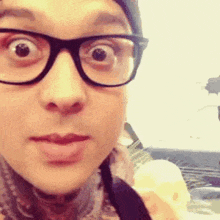 a woman wearing glasses and a scarf is making a funny face .