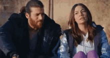 a man and a woman are sitting next to each other looking at something .