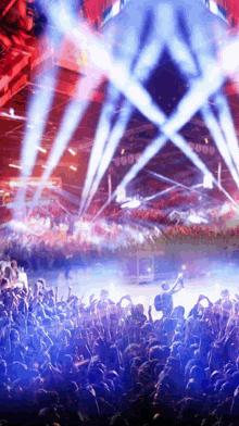a crowd of people at a concert with blue lights coming out of the ceiling
