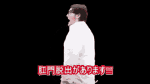 a man in a white shirt stands in front of a black background with chinese writing on it