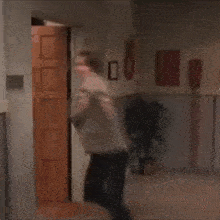a man is standing in a hallway with his arms outstretched in front of a door .