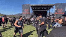 a crowd of people are standing in front of a stage at a mayhem festival .