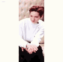 a young man with red hair is sitting on a couch wearing a white shirt .