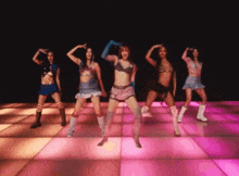 a group of women are dancing on a pink and orange floor