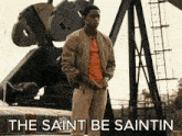 a man standing in front of a large machine with the words the saint be saintin