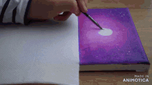 a person is painting a purple and white galaxy on a canvas made in animatica