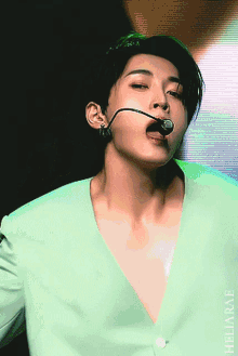 a close up of a man wearing a green jacket and a microphone in his mouth