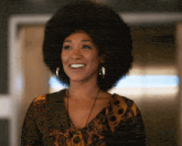 a woman with a large afro is smiling and wearing earrings