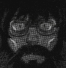 a black and white photo of a person 's face with glasses and a beard .