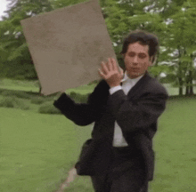 a man in a suit is holding a piece of cardboard in his hands .