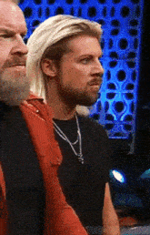 a man with blonde hair and a beard stands next to another man with a beard