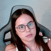 a young girl wearing glasses is sitting in a chair