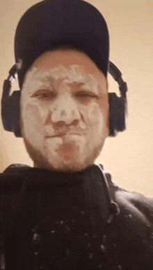a man wearing headphones and a hat has a white face painted on it