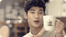 a young man is holding a cup that says angel in us coffee