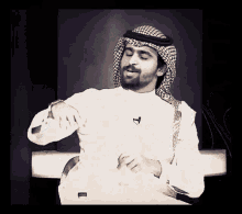 a man wearing a head scarf and a white shirt has a microphone on his collar