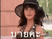 a woman wearing a hat and a leopard print dress is standing in front of a building .
