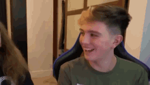 a young man is sitting in a chair laughing while a woman looks on .