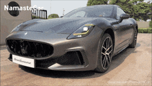 a gray sports car with a namaste car logo