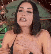 a woman in a bikini top is making a funny face while holding her chest .