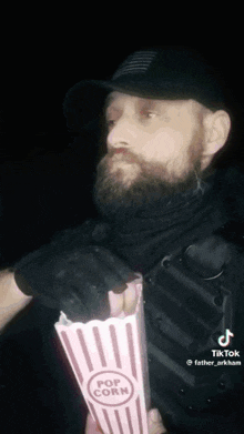 a man with a beard is holding a bag of popcorn .
