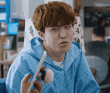 a man in a blue striped shirt is holding a makeup brush .