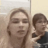 two women are standing next to each other in a room and talking .