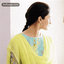 a woman in a yellow dress and blue top is standing in front of a wall .
