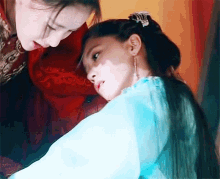 two women are standing next to each other and one is wearing a blue dress