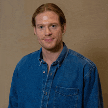 a man wearing a blue denim shirt is smiling