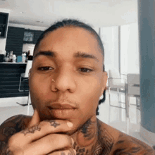 a man with tattoos on his arms and neck is taking a selfie in a kitchen .