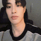 a close up of a young man 's face wearing a gray and black sweater .
