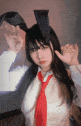 a woman wearing bunny ears and a red tie is making a peace sign