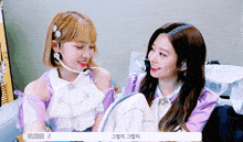 two girls are sitting next to each other and one has a microphone in her ear