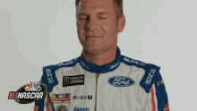 a man in a ford racing uniform is making a funny face .