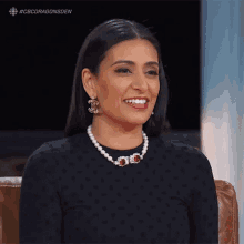 a woman wearing a pearl necklace and earrings smiles