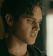 a close up of a young man 's face with curly hair looking at something .