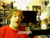 a man in a red shirt says joseph in front of a monitor