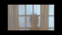 a person is standing in front of a window with a white curtain
