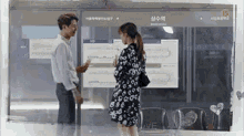 a man and a woman are standing next to each other in front of a sign .