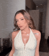 a woman wearing a white halter top has a tattoo on her shoulder