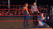 two wrestlers are in a wrestling ring with a referee and the word nxtuk in the background