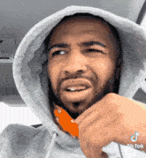 a man wearing a hooded sweatshirt has a tiktok watermark on his face